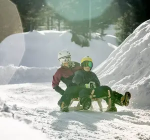 Mutter und Kind auf der Rodelbahn im Winter in Imst